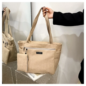 Dettaglio della borsa tote in velluto a coste beige con etichetta e piccola pochette