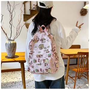 Detailansicht eines rosa Comic-Bär-Rucksacks am Modell in einer Café-Umgebung
