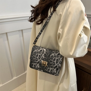 Chic leopard print crossbody bag with gold buckle on elegant white coat outfit