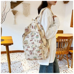 Detail eines Canvas-Rucksacks mit Bärenprints und vorderer Reißverschlusstasche in Beige
