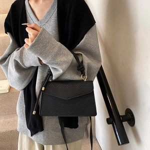 Borsa a tracolla minimalista nera a trama intrecciata con dettagli oro su modella
