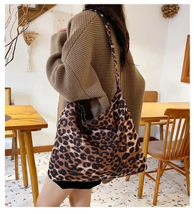 Detailed side view of large leopard print tote bag worn over the shoulder in a cafe