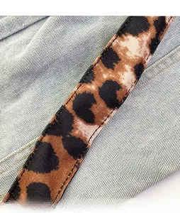 Detail of leopard print woven shoulder strap on light blue denim tote bag with twill texture
