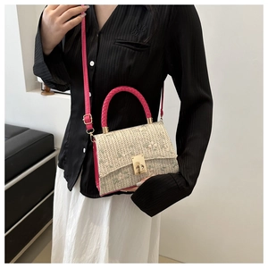 Détail de broderie florale et fermoir doré sur sac tressé beige avec poignée rose vif