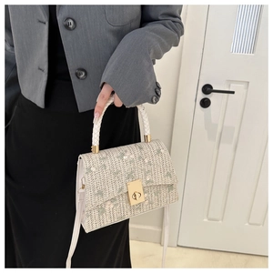 Détail d'un sac à main en paille tissée avec broderie florale et anse tressée