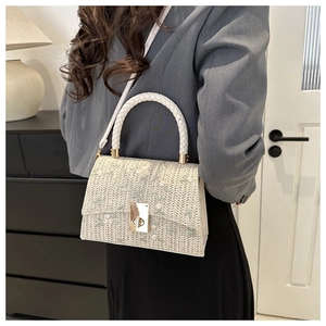 Détail du sac à bandoulière en paille tissée avec broderie florale et fermoir doré