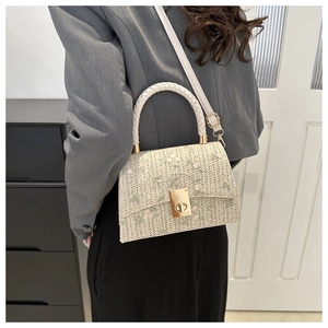 Détail du sac à main tissé beige avec broderie florale et fermoir doré rotatif