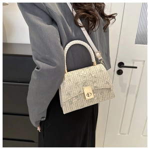 Détail d'un sac bandoulière tissé avec broderie florale vert clair et fermoir doré chic