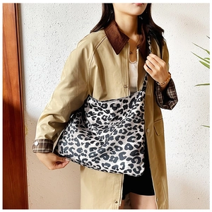 Close-up of leopard print canvas bag with wide strap on khaki trench coat