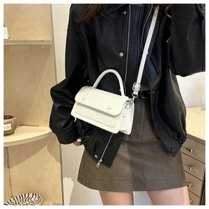 Close-up of white leather handbag with curved handle and silver decorative buttons