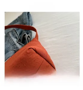 Close-up of orange canvas fabric texture and fine stitching on the stylish shoulder bag