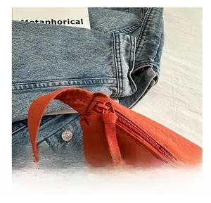 Close-up of smooth zipper with fabric pull tab on orange minimalist shoulder bag