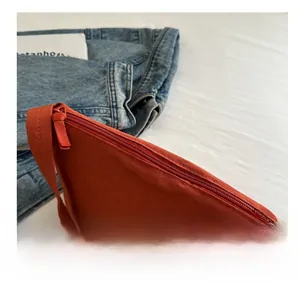 Top view of a bright orange minimalist bucket bag on a casual lifestyle background