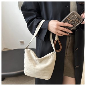 Detail of minimalist beige pleated shoulder bag with long zipper puller and half-moon shape