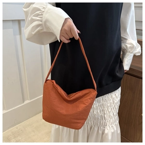 Close-up of orange crescent bucket bag showing nylon fabric texture and shoulder strap