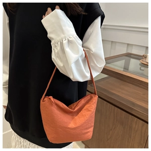 Detail of bright orange pleated hobo bag showing the unique texture and shoulder strap