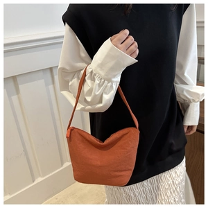 Détail du sac seau plissé orange vif montrant la fermeture éclair et le textile