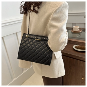 Detailed view of black quilted faux leather with elegant gold chain shoulder strap