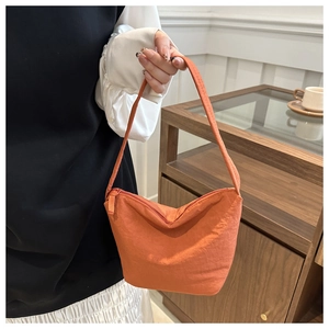 Detail of trendy orange nylon hobo bag featuring crinkled texture and sleek zipper closure
