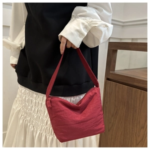 Detailed close-up of dark red canvas underarm bag with zipper and wide strap