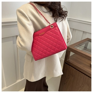 Macro detail of deep pink quilted tote bag with golden metal chain strap and leather texture