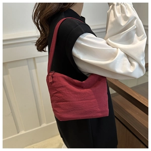 Detail showing dark red nylon bucket bag with crinkled texture on a female model
