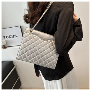 Detail of silver quilted shoulder bag featuring metallic chain and glossy finish