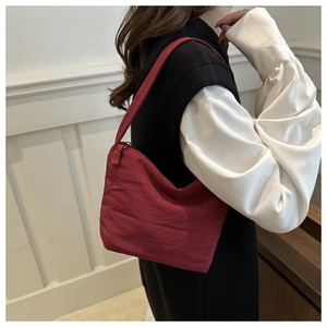 Détail du sac à bandoulière en toile rouge foncé avec texture et fermeture éclair