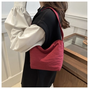Détail du sac seau bordeaux en nylon avec texture souple porté par un mannequin