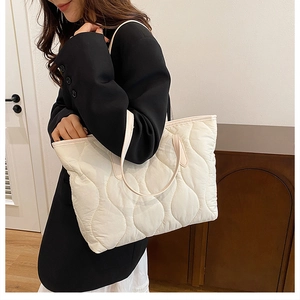 Quilted large tote bag in cream white with wave pattern embroidery shown on model