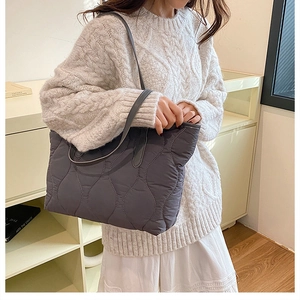 Close-up of a grey wave-quilted tote bag showing soft padded texture and shoulder strap