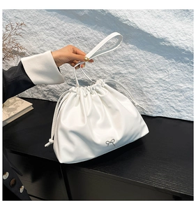 Detail of white PU leather cloud bag featuring drawstring pleats and silver bow accent