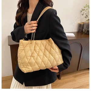 Dettaglio della borsa tote beige trapuntata con tracolla a catena e trama in nylon