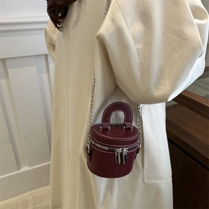 Mini burgundy leather bucket bag with silver chains and double zippers shown on model