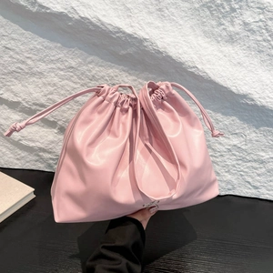 Pink pleated drawstring shoulder bag with silver bow accent and soft leather texture