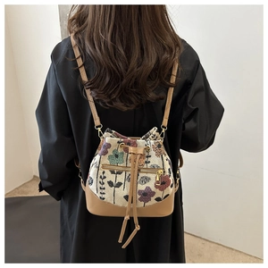 Detalle de la textura de jacquard floral y cordón de cuero en el bolso tipo cubo bandolera