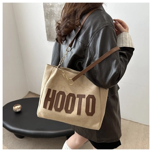 Detail of beige suede tote bag with HOOTO letter patch and brown leather shoulder strap