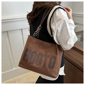 Close-up of brown suede tote bag featuring HOOTO embroidery and gold chain details