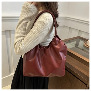 Detail of burgundy ruched cloud tote bag with pleated leather texture and shoulder strap