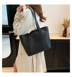 Detail of a black minimalist tote bag with FASHION embossed patch and large capacity
