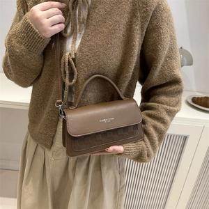 Chic brown leather shoulder bag with checkerboard texture shown on a stylish model