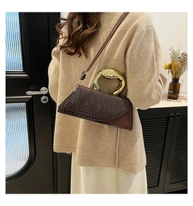 Detailed close-up of dark brown crocodile pattern texture and sleek gold metal handle