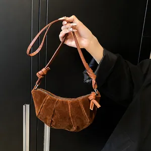 Dettaglio borsa a mezzaluna in pelle scamosciata marrone con pieghe e tracolla annodata
