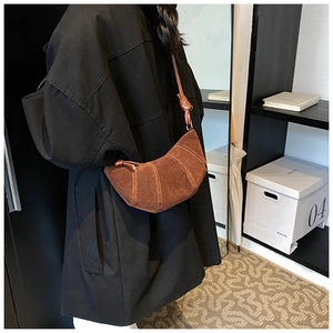Dettaglio di una borsa a croissant marrone pieghettata con texture opaca e tracolla