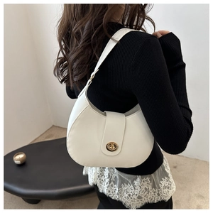 Detailed shot of white leather underarm bag with gold turn-lock closure on black outfit