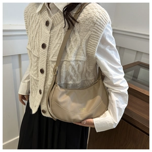 Model showing a beige lychee pattern leather half-moon crossbody bag with golden logo