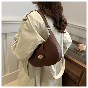 Detailed close-up of dark brown vintage saddle bag with gold metal lock on light background