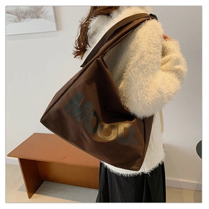 Detail showing the dark brown canvas tote bag with MOOD lettering on model's shoulder