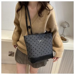 Polka dot canvas tote bag with black bow detail and leather base held by female model