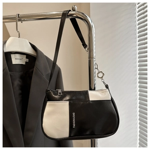 Detailansicht der schwarz-weißen Leder-Achseltasche mit Blumenanhänger am Metallständer